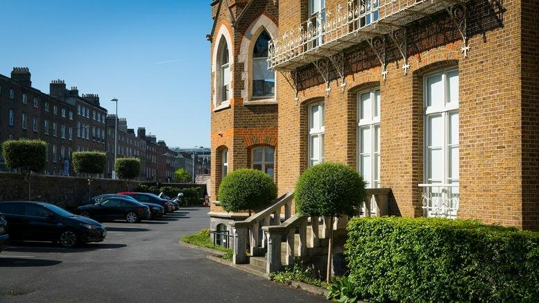 Exterior brick facade of Hamilton House, 28 Fitzwilliam Place, Dublin, Ireland showing stone steps and greenery.