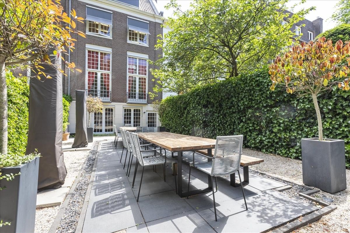 Exterior view of the historic brick building at Herengracht 280 with a stone patio and outdoor dining table.