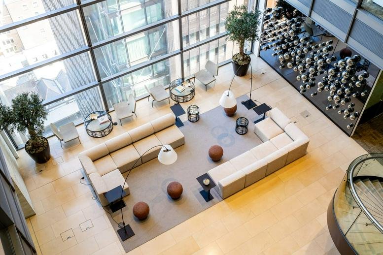 High-angle view of a sunlit communal lounge with cream sectional sofas.