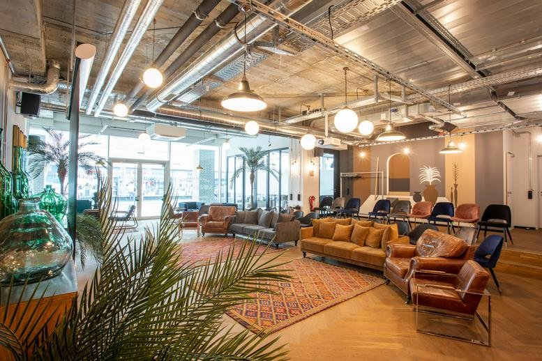 Spacious communal lounge at Herzogspitalstrasse 24 with diverse seating and industrial ceilings.