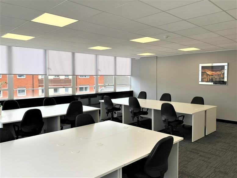 Bright open-plan workspace at Highlands House with white desks and ergonomic black chairs.