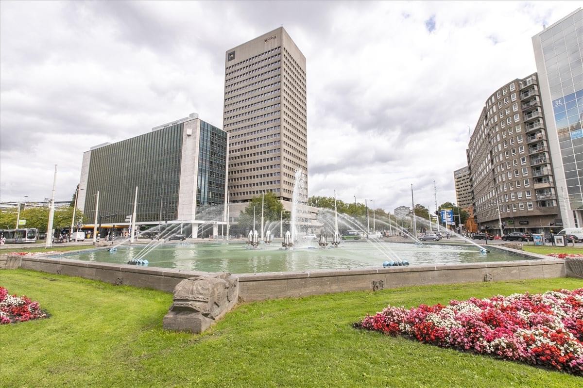 Exterior view of the high-rise building at Hofplein 20 with a large fountain in the foreground.