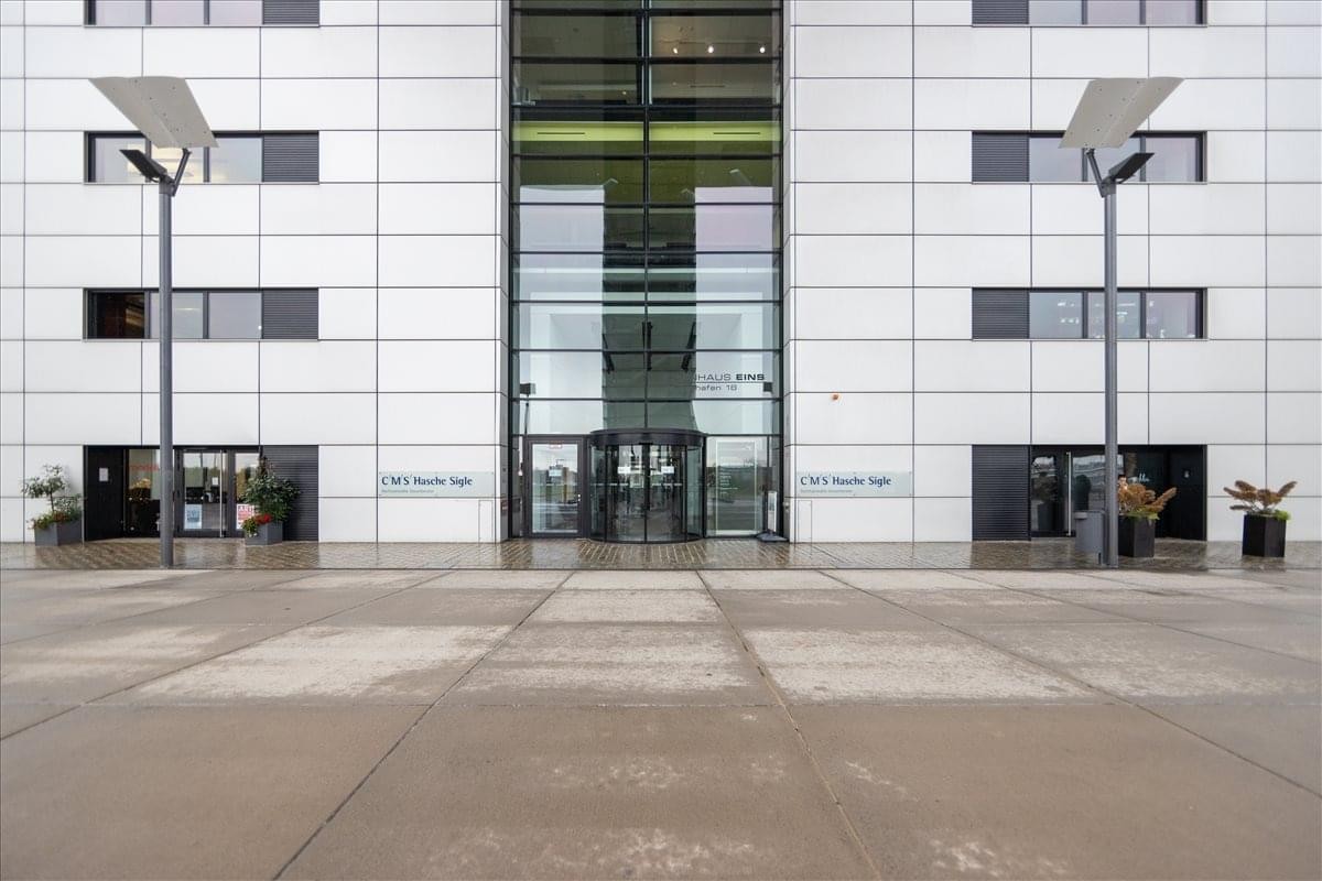 Exterior view of the white facade and glass entrance at Im Zollhafen 18, Kranhaus 1.