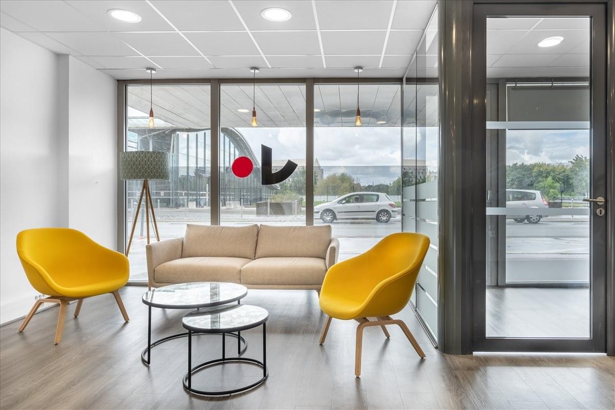 Vibrant lounge area with yellow armchairs and a cream sofa by large windows.
