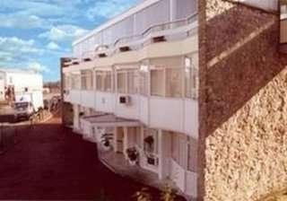 Exterior view of the white multi-story Jolyon House with large windows and a stone accent wall.