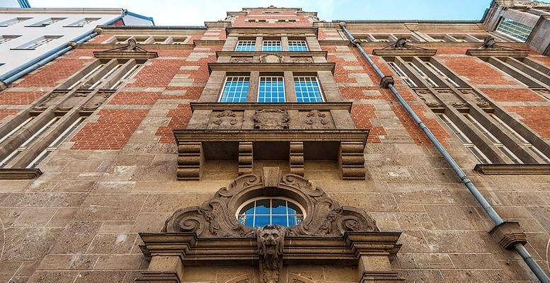 Exterior facade of the historic Kaiserliche Postdirektion with red brick and ornate stone carvings.