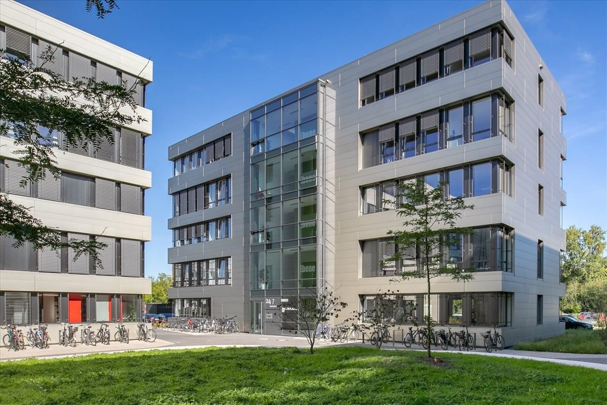 Modern multi-story exterior of Karl-Ferdinand-Braun-Str. 5 with glass entrance and green lawn.