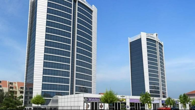 Exterior view of the twin glass-facade skyscrapers of Hukukçular Towers under a clear blue sky.