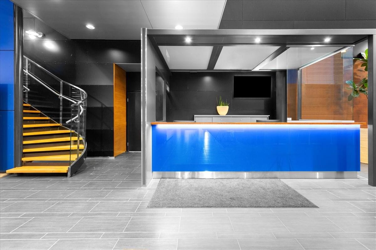 Sleek blue-lit reception desk at Keilaranta 1, Espoo, Finland with a spiral staircase.