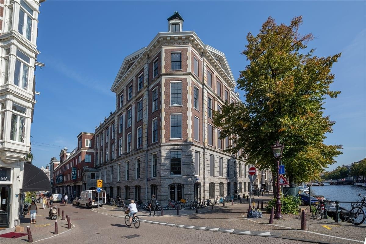 Exterior view of the historic brick building at Keizersgracht 555 on a sunny canal corner.
