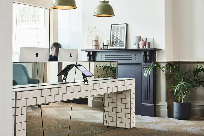 Tiled reception desk with computers and a classic black fireplace.