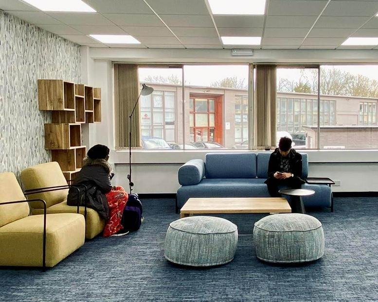 Spacious lounge at Kingspark Centre, 152-178 Kingston Road, with a blue sofa, yellow chairs, and modern shelving.