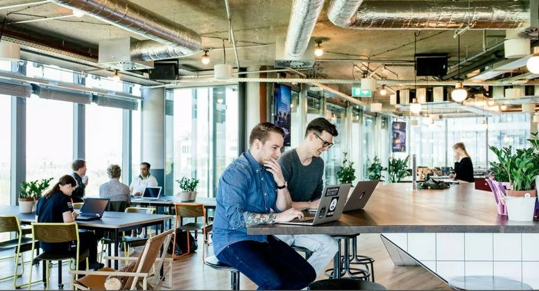 Large open-plan office area with modern industrial ceilings and various seating zones.