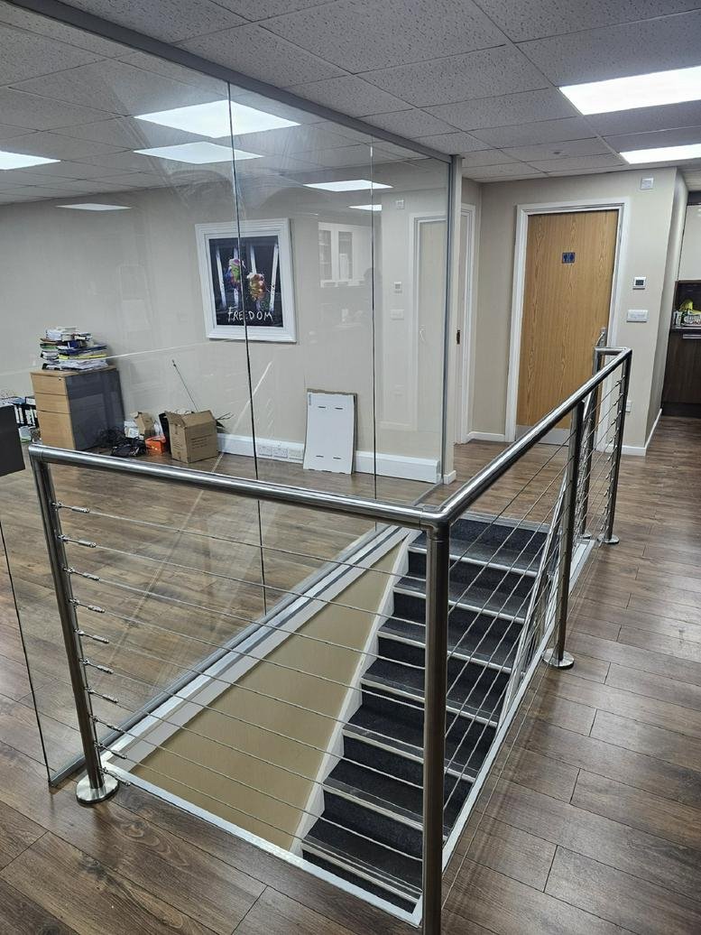 Entrance area of Leverford House, 219 Kingsbury Road featuring a staircase with metal railings and glass partitions.