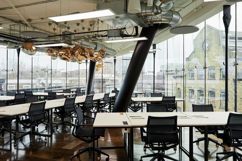 Spacious open-plan workspace with multiple desks, floor-to-ceiling windows and city views.