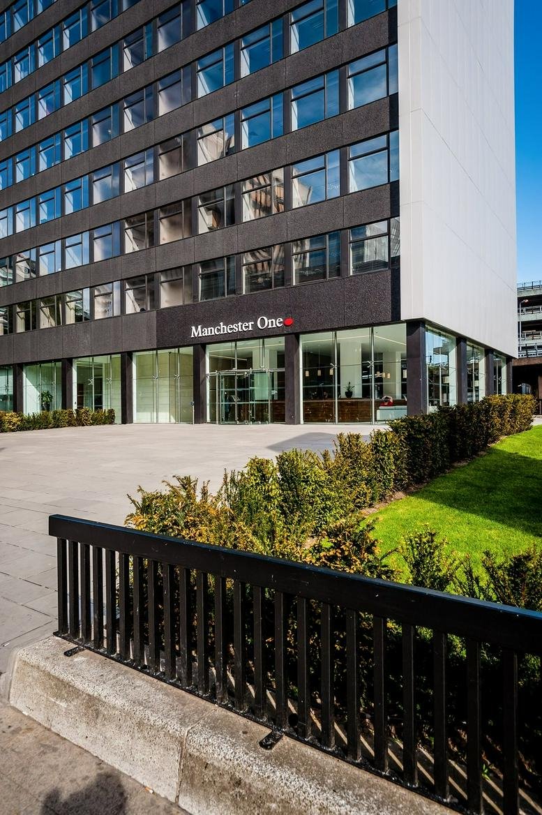 Ground level view of the Manchester One building facade and landscaped entrance.