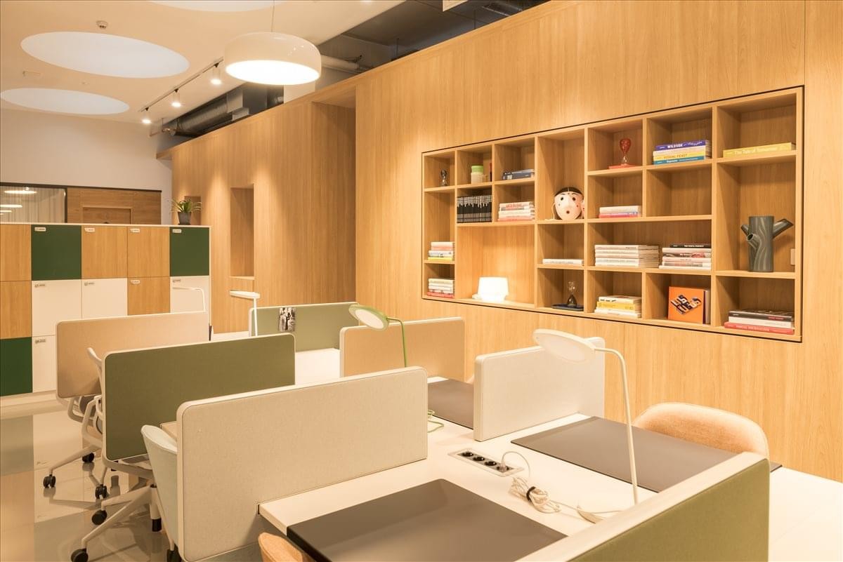 Modern coworking space at Mannerheiminaukio 1 with light wood paneling and minimalist desks.