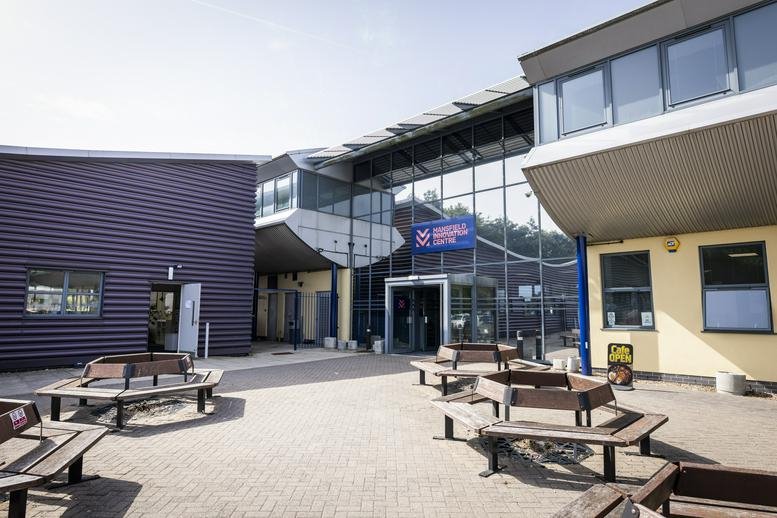 Exterior entrance and courtyard of the Mansfield i-Centre with wooden hexagonal benches.