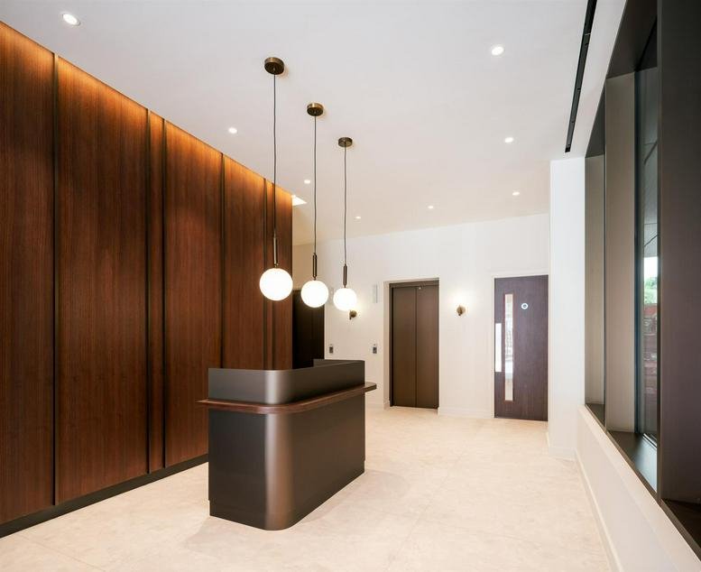 Sleek minimalist reception desk with wood panelled walls and globe pendant lighting.
