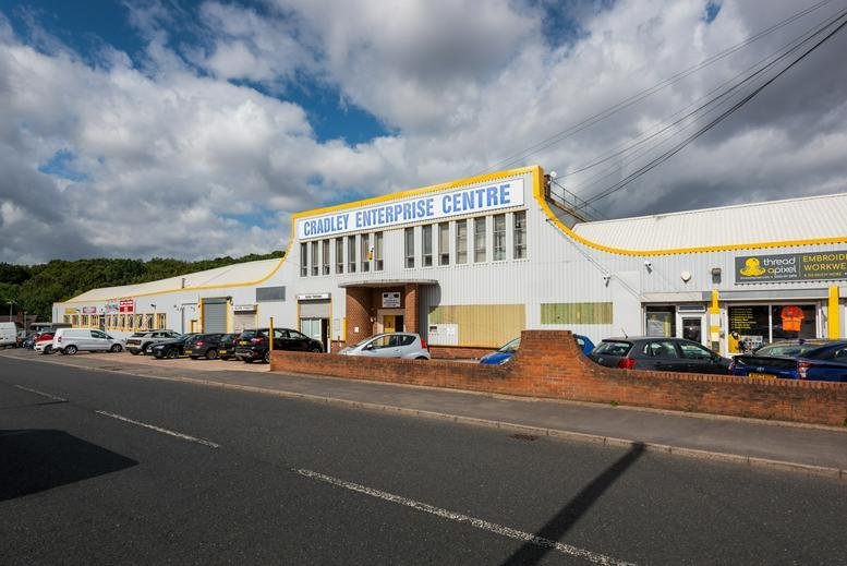 Exterior view of the white and yellow facade of Cradley Enterprise Centre under a blue sky.