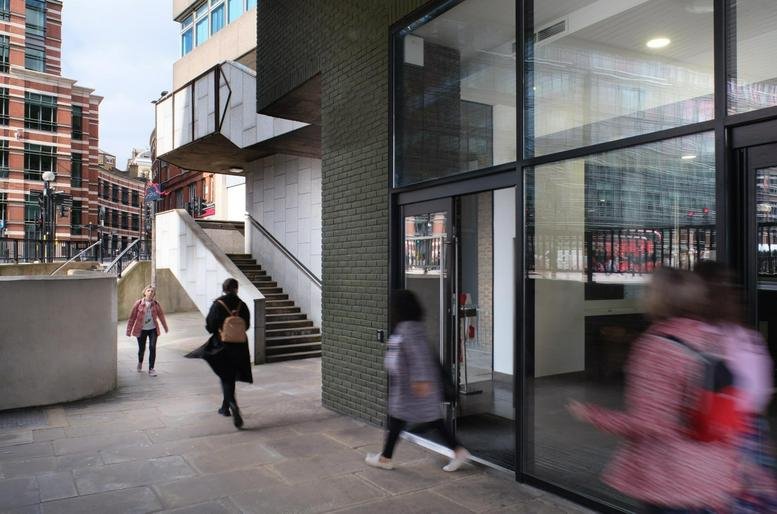 Exterior entrance of Mermaid House, Puddle Dock with pedestrians passing by large glass windows.