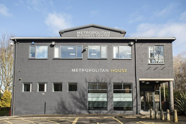 Exterior view of Metropolitan House with parking area and trees.