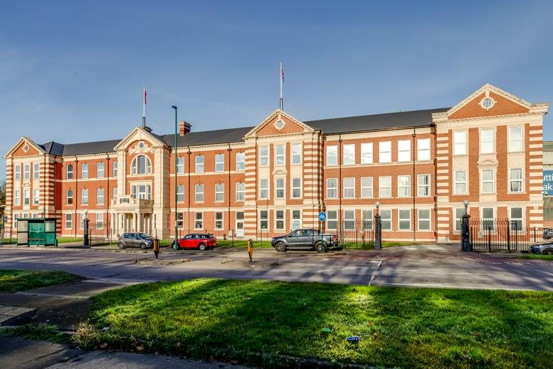 Full exterior view of the large Victorian-style office building with a green lawn.