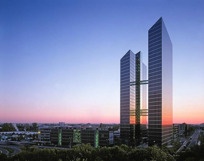 Exterior view of the glass-facade Mies-van-der-Rohe-Str. 4 building towers at sunset.