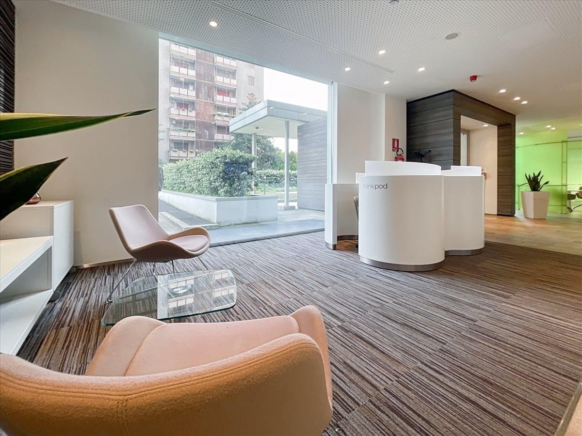 Spacious reception lounge at Milan Viale Monza with white circular desks and views of the street.