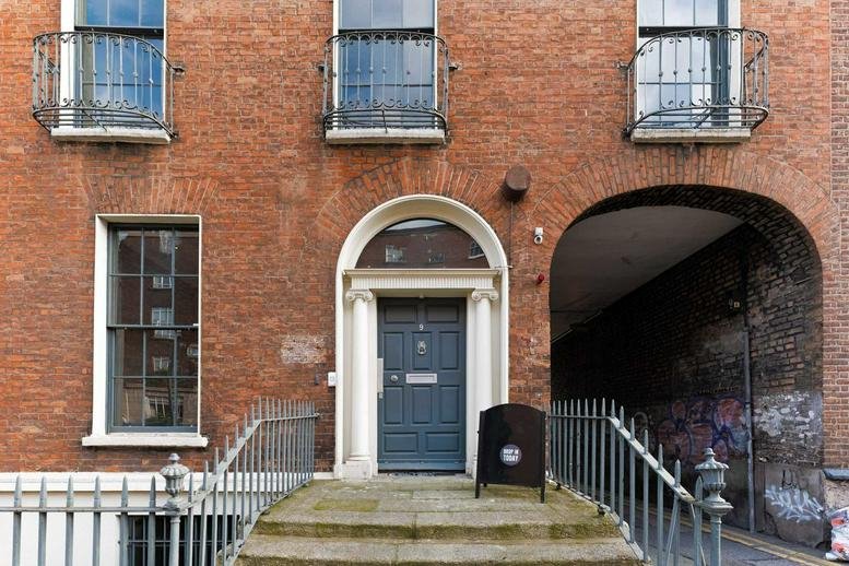 Exterior view of the brick facade and arched entrance at No. 9 Pembroke Street, Dublin, Ireland.