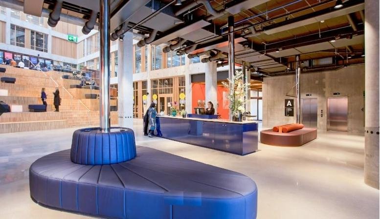 Modern lobby at Nordenskiöldsgatan 24, Malmo with a sleek blue reception desk and unique curved seating.