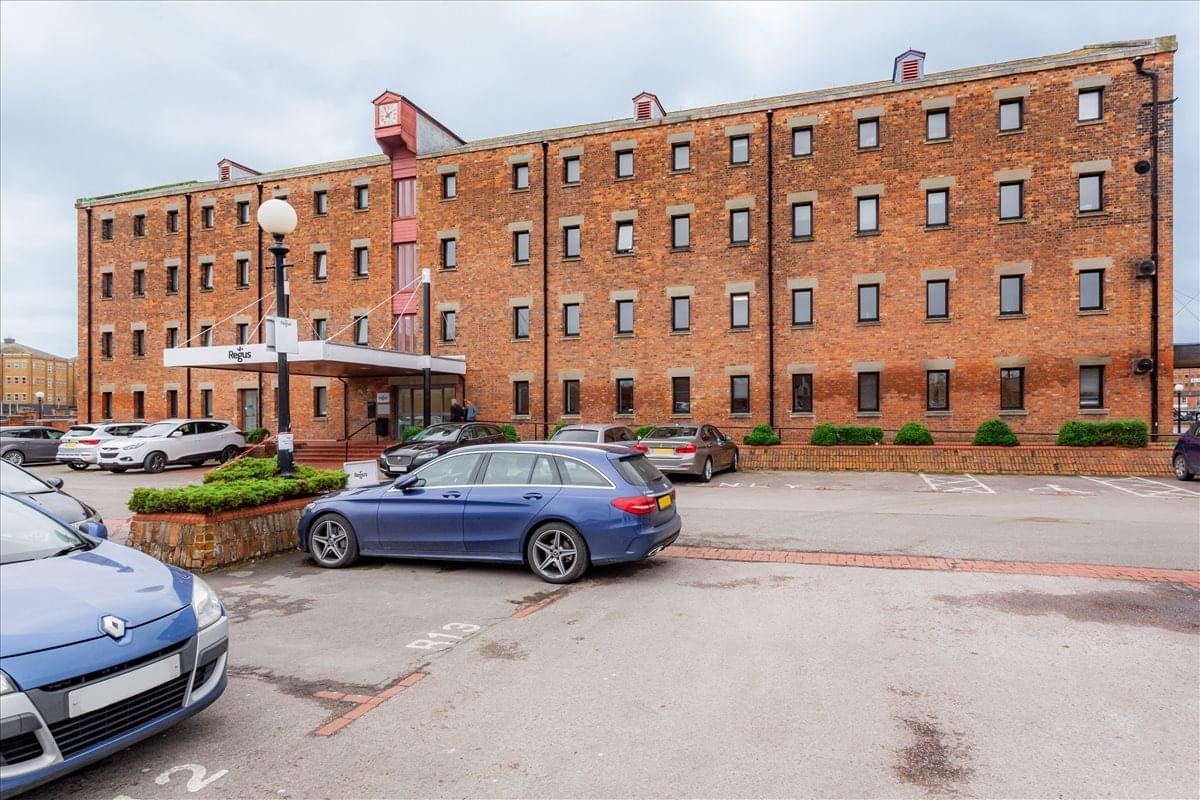 Exterior of the red brick North Warehouse, Gloucester docks with a car park in front.