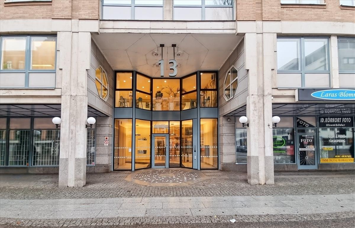 Exterior entrance of the building at Odinsgatan 13, Gothenburg, featuring glass doors and stone pillars.