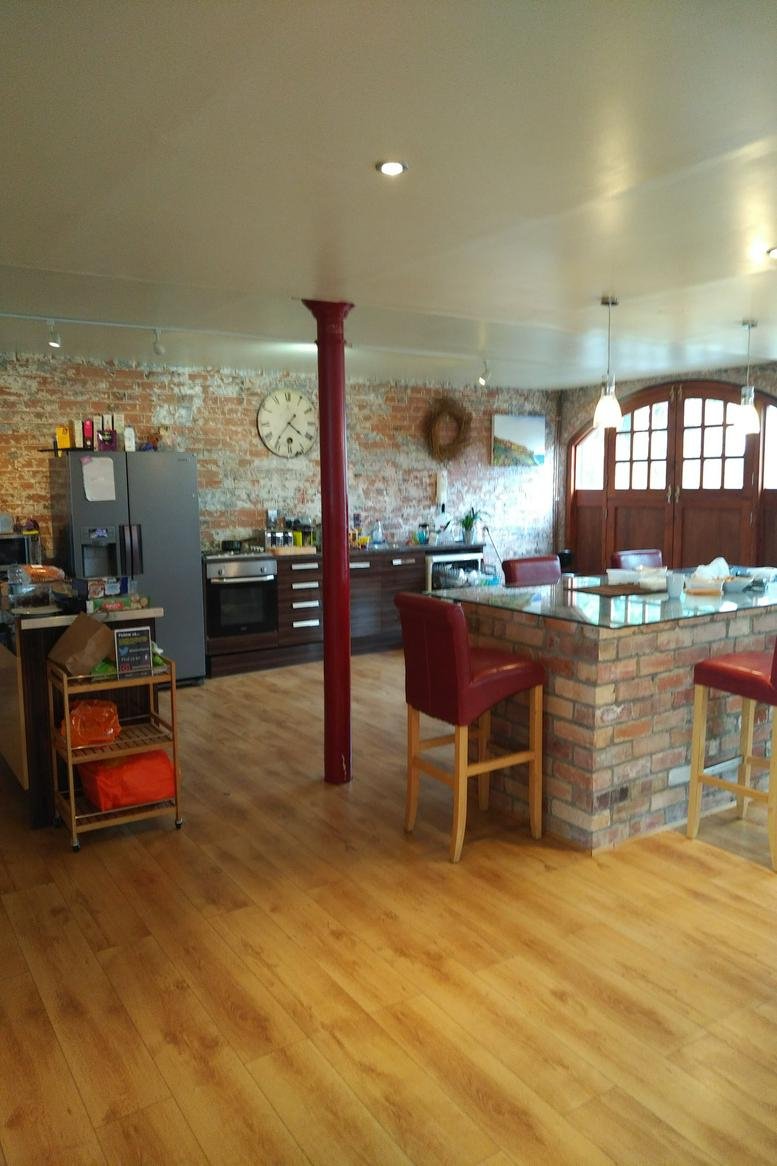 Spacious communal kitchen and dining area with exposed brick walls and wooden floors.