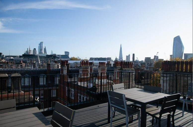 Roof terrace at Serviced Offices on The Strand, London featuring wooden tables and views of the Shard.