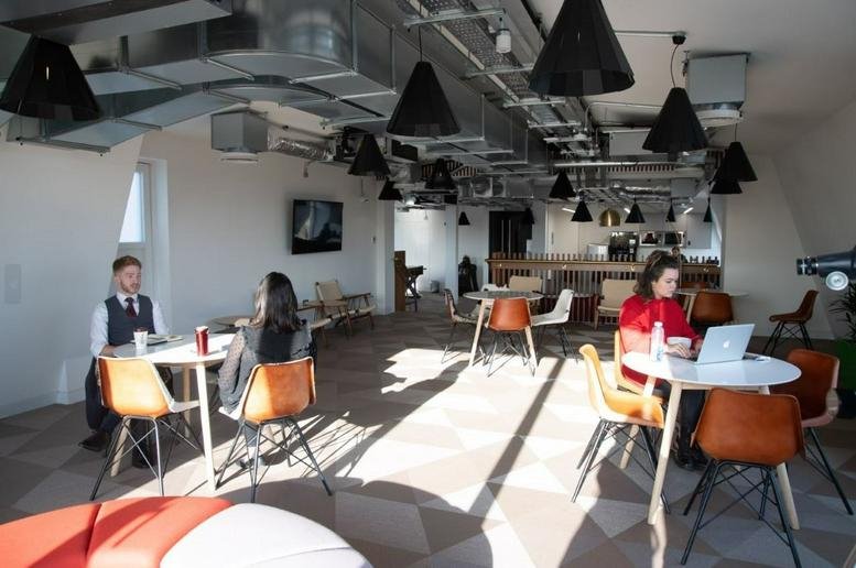 Sunlit coworking lounge at Serviced Offices on The Strand, London with mid-century modern furniture.