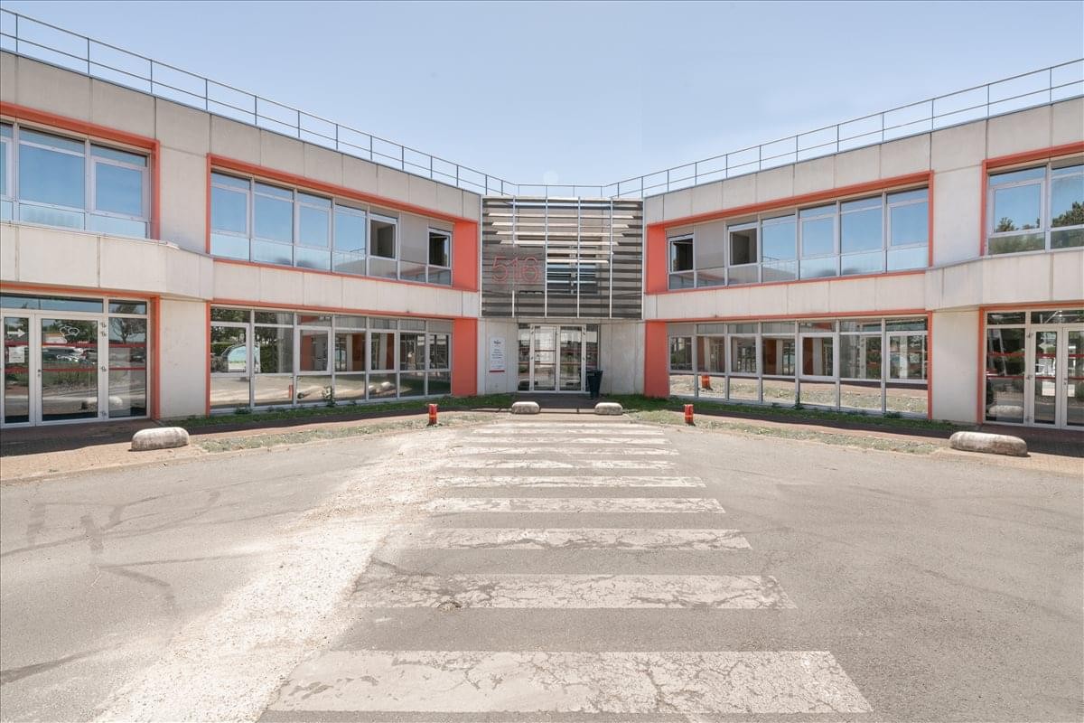 Modern exterior facade of Building 516 at Orlytech zone with large glass windows and a zebra crossing.