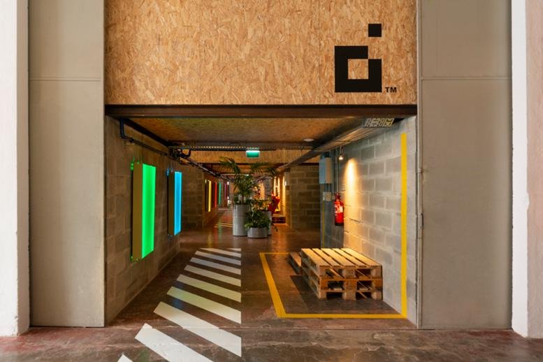 Reception entrance featuring industrial concrete walls and a large wooden logo at Armazem 17 A, Porta E.
