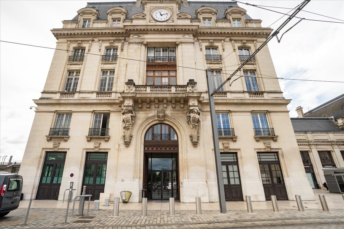 Grand stone exterior of Parvis Louis Armand, Gare de Bordeaux Saint-Jean with ornate carvings and a clock.