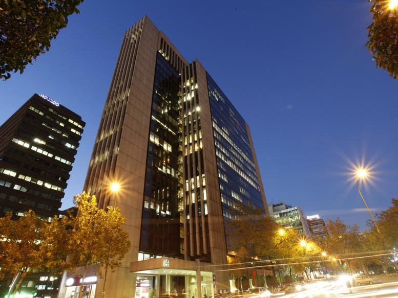 Exterior view of the towering glass-facade Cuzco IV Building at twilight.