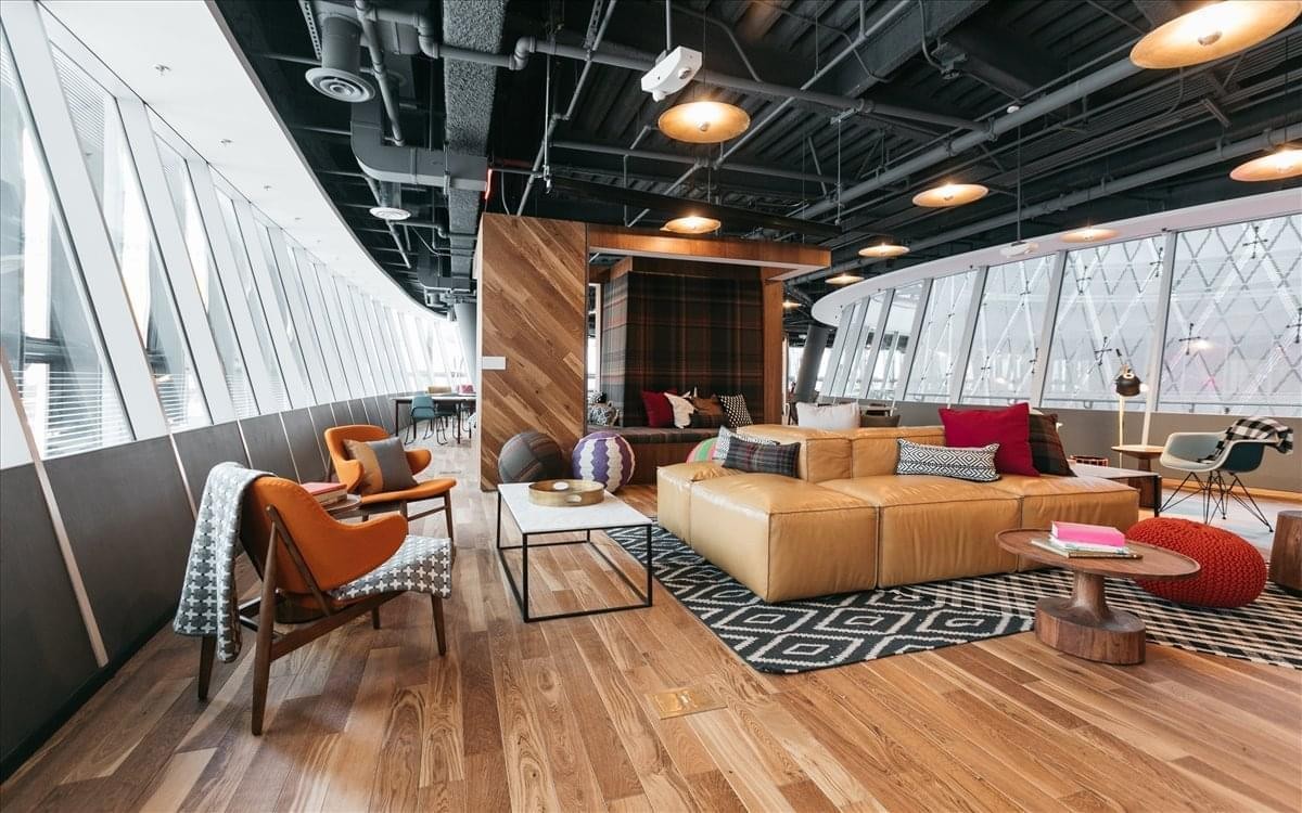 Spacious communal lounge at Paseo De La Castellana 77 with modern furniture and floor-to-ceiling windows.