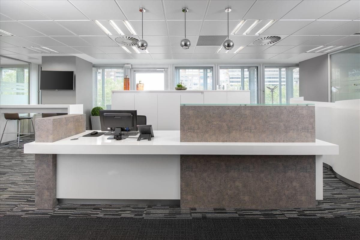 Minimalist reception area at Paseo de la Castellana 93, Madrid, Spain with a modern grey-panelled front desk.