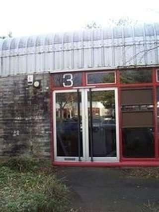 Exterior entrance of Pentland Court, Saltire Centre, Glenrothes, Scotland featuring glass doors and a red frame.