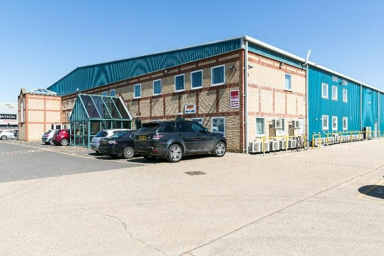 The industrial exterior of Pinnacle House, Newark Road, Peterborough, Cambridgeshire with a glass entrance.