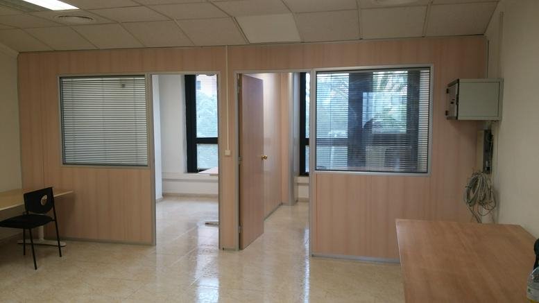 Spacious reception area with light wood partitions and a private office entrance at 5 Calle Pintor Javier Soler.