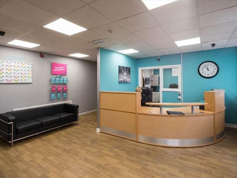 Bright reception area with a curved wooden desk, teal accent wall, and a black leather sofa at Planetary Business Centre.