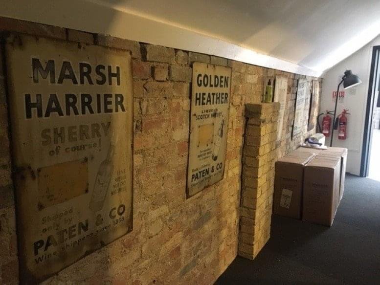 Exposed brick hallway at PMA House featuring vintage sack artwork and warm lighting.
