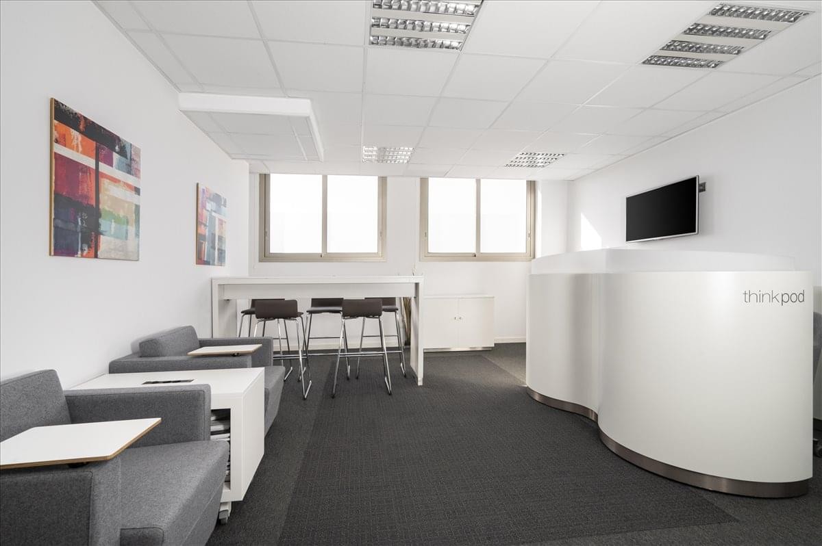 Communal breakout area at Gremi de Sabaters 21 featuring grey armchairs and a modern curved coffee station.