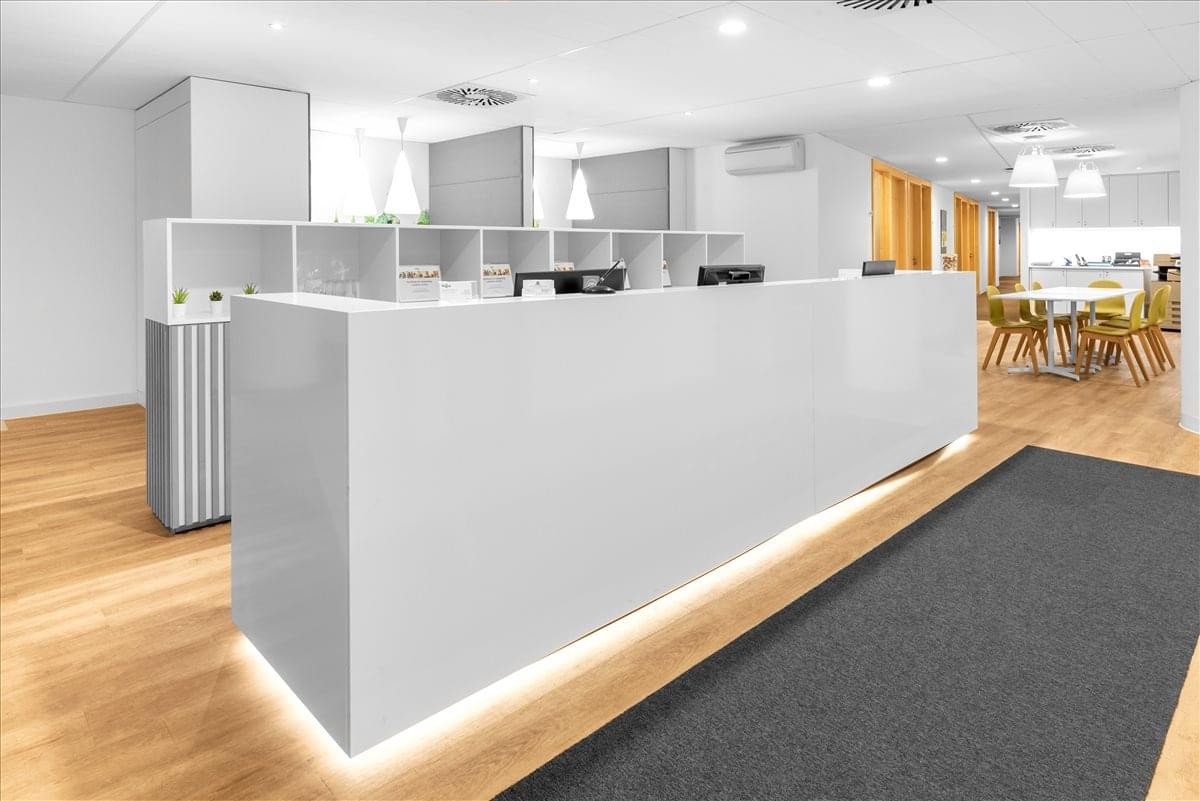 Bright white reception desk with minimalist shelving and integrated lighting.