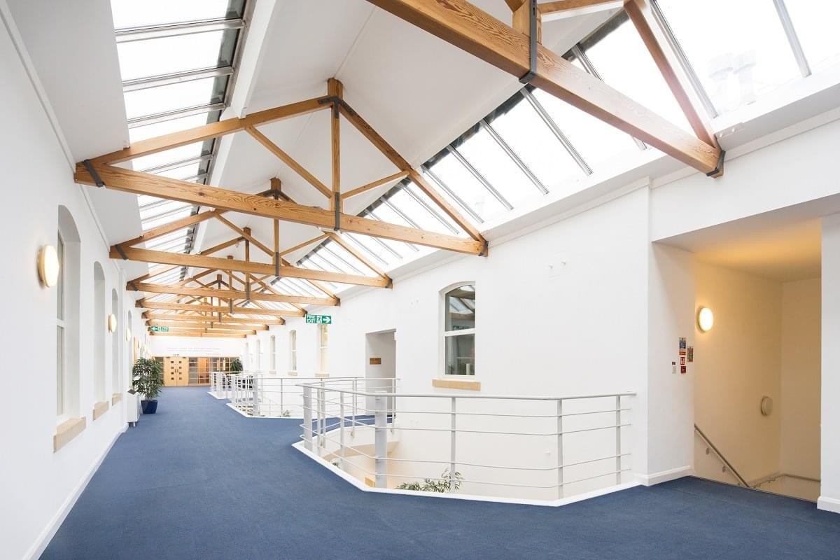 Spacious communal atrium at Preston Technology Centre with wooden rafters and bright skylights.